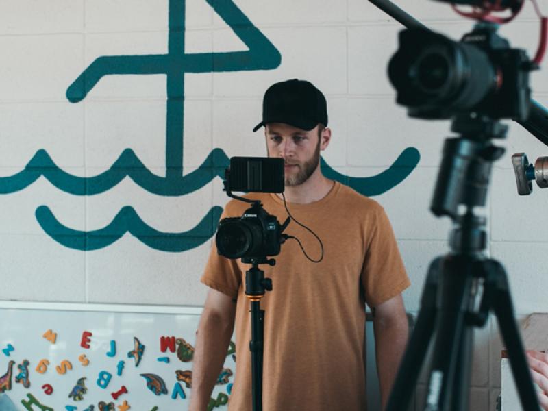 Students surrounded by film equipment filming an interview.